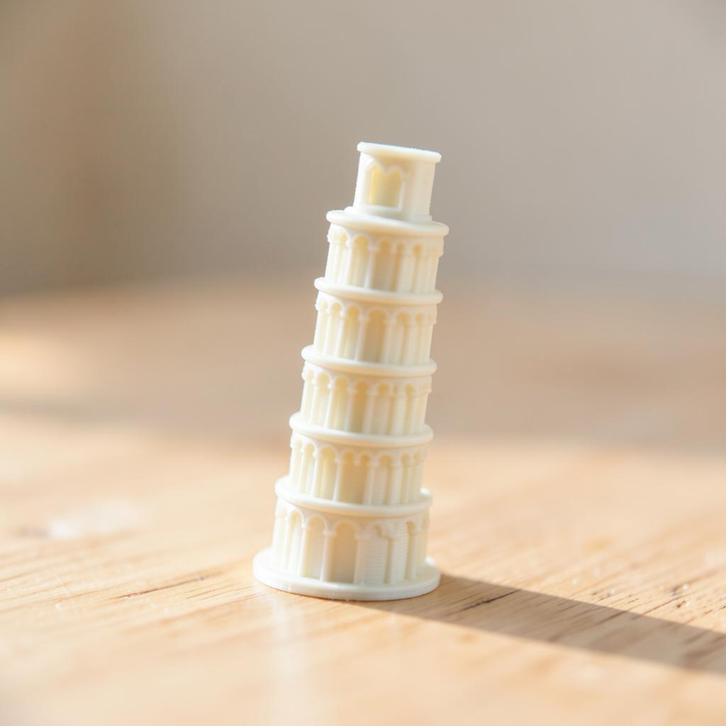 Miniatura 3D da Torre de Pisa em filamento branco osso sobre mesa de madeira
