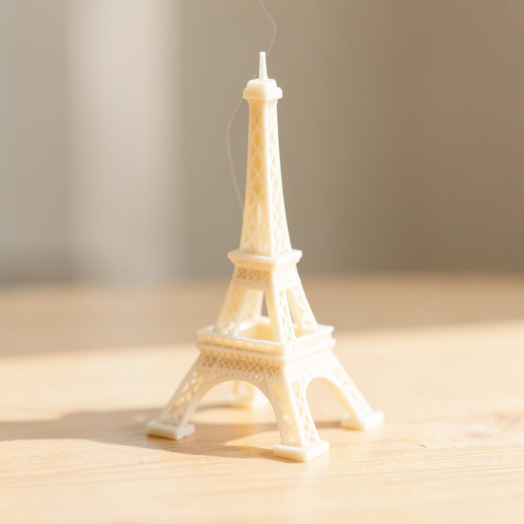 Miniatura 3D da Torre Eiffel em filamento branco osso sobre mesa de madeira